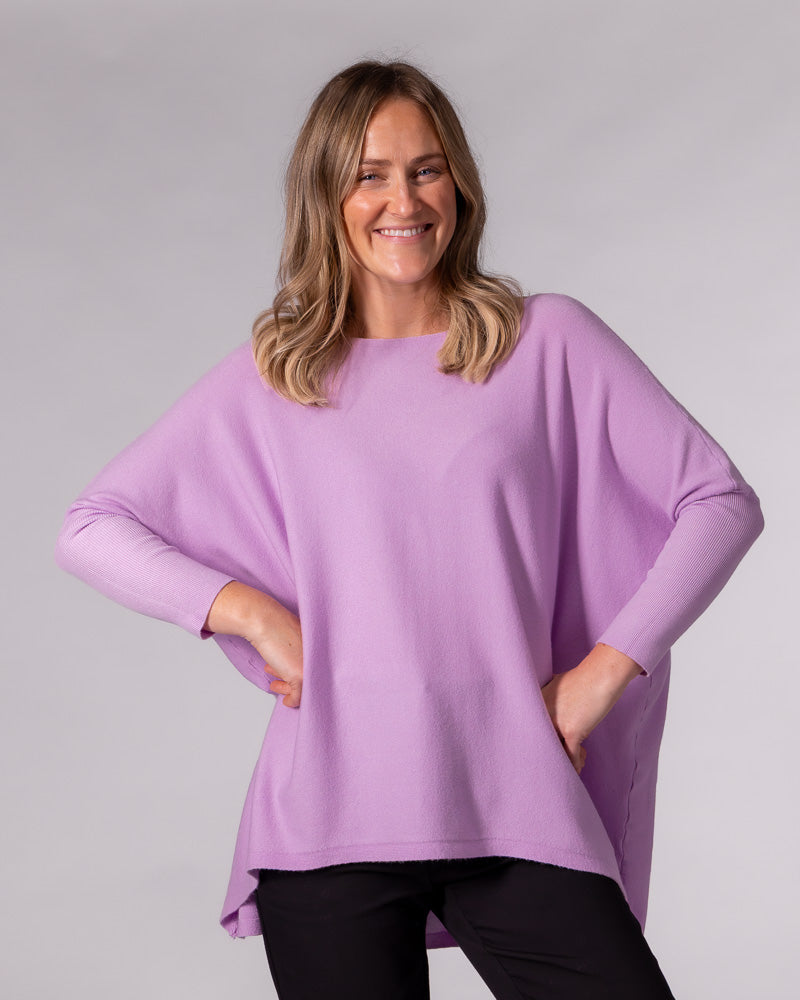 Oversized lilac cotton knit jumper featuring a wide boat neckline, fitted ribbed lower sleeves, and a hi-low hem.