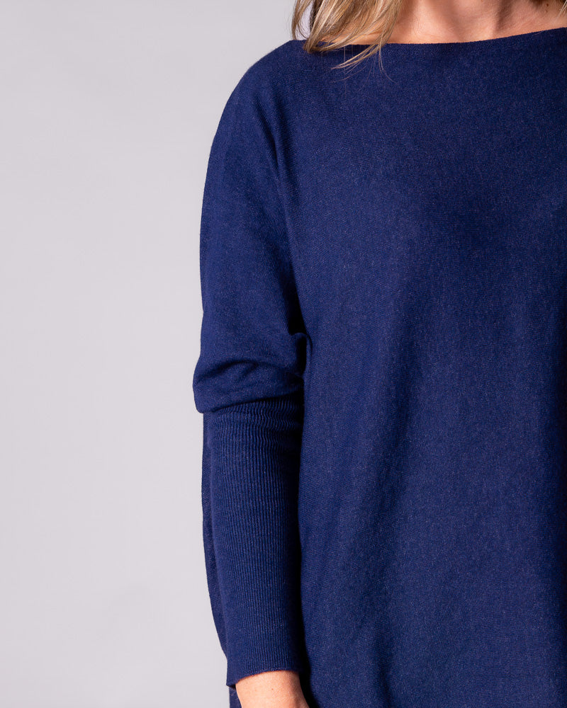 Close-up of the navy knit top, displaying the contrast between the long fitted ribbed sleeves and loose body.