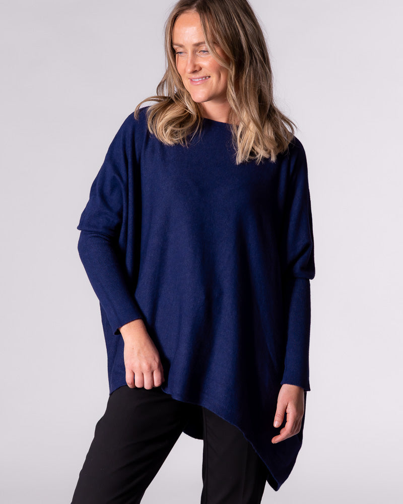 Front half-body shot of the oversized navy knit top demonstrating the comfortable drape and modern hi-low hemline.