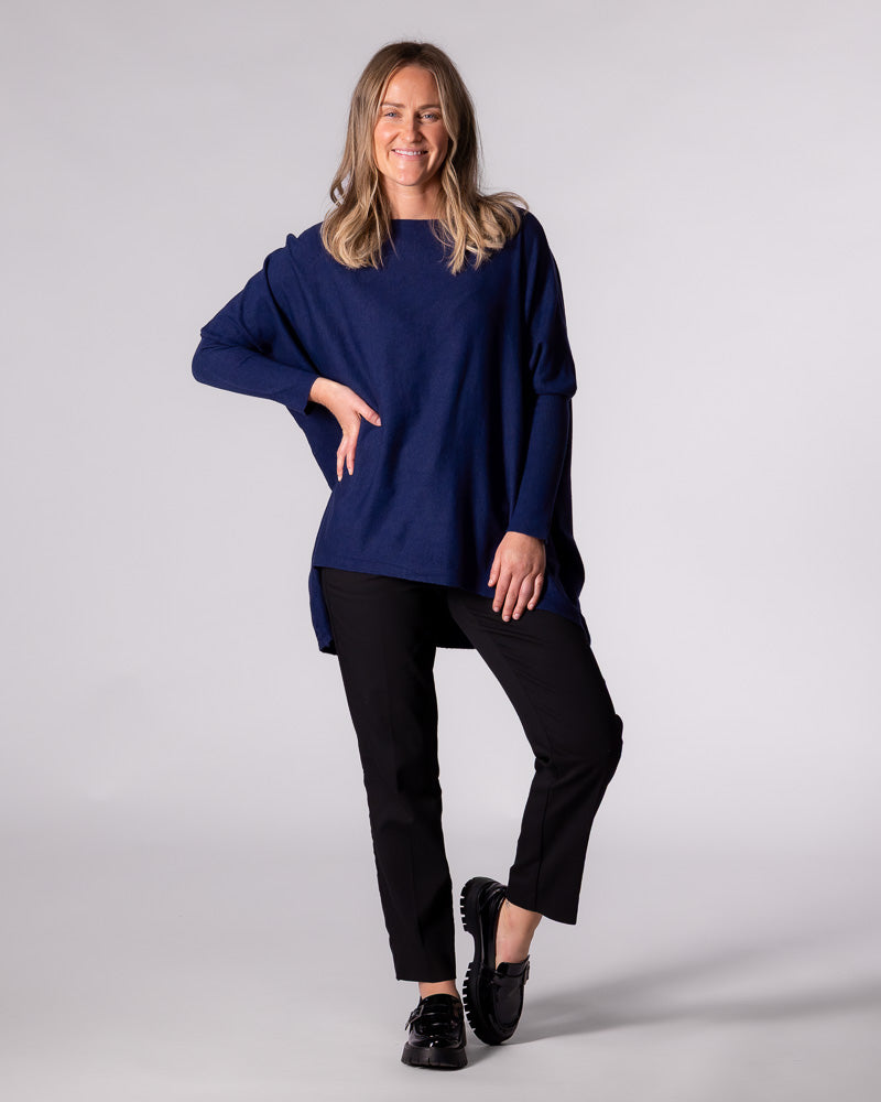 Full-length styling of the navy Karma Kameleon knit top paired with tailored black pants and chunky loafers.