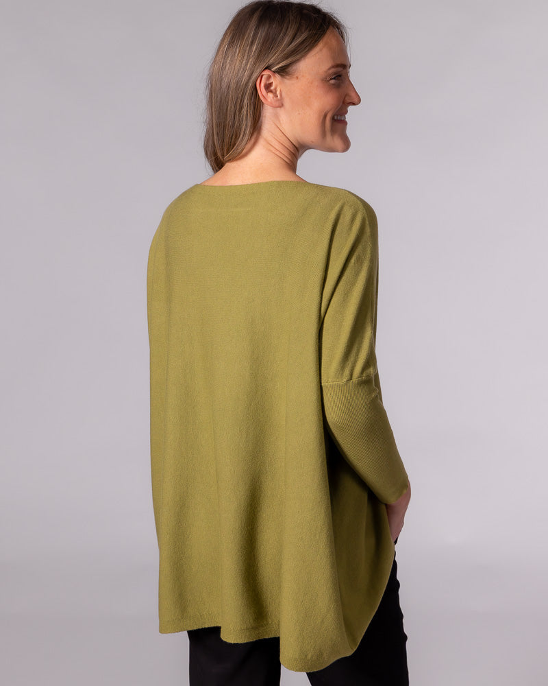 Back view of an oversized olive green cotton jumper highlighting the draped back design and fitted ribbed sleeves.