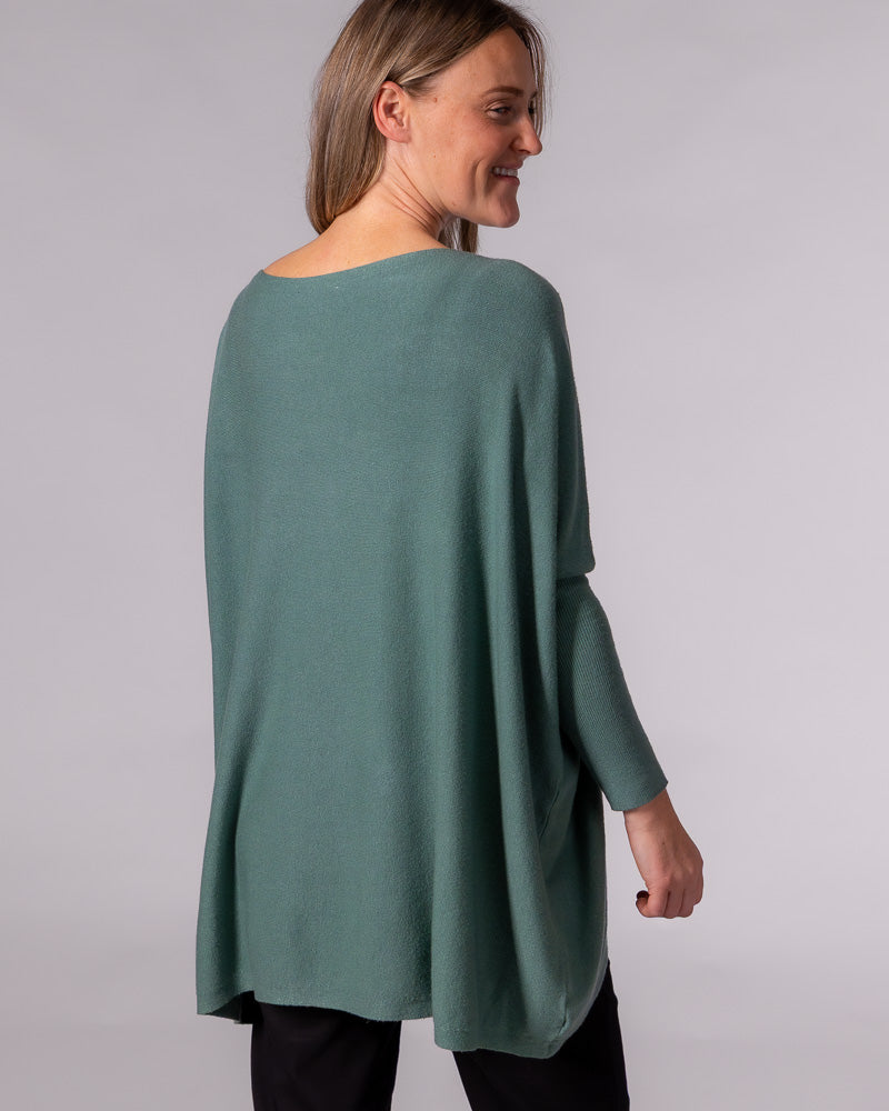 Oversized sage green cotton jumper featuring a draped back, wide neckline, and drop shoulders with a fitted sleeve.