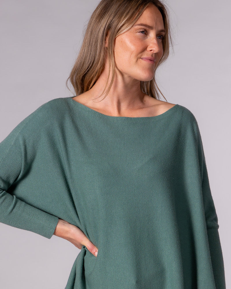 Oversized sage green cotton knit jumper showcasing an elegant wide boat neckline, drop shoulders, and fitted ribbed cuffs.