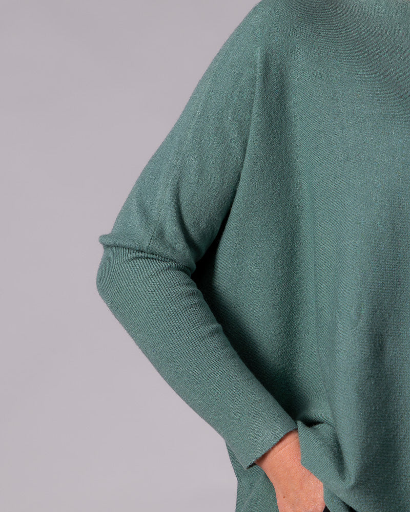 Sage green cotton knit jumper showcasing the relaxed drop shoulder and fitted ribbed sleeve.