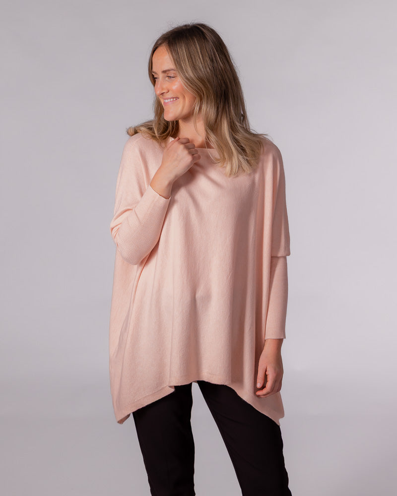 Oversized soft pink cotton jumper featuring a wide neckline, draped body, drop shoulders, and fitted ribbed sleeves.