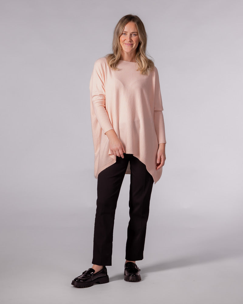 Oversized soft pink cotton knit jumper with a wide boat neckline, drop shoulders, and a draped hi-low hem.