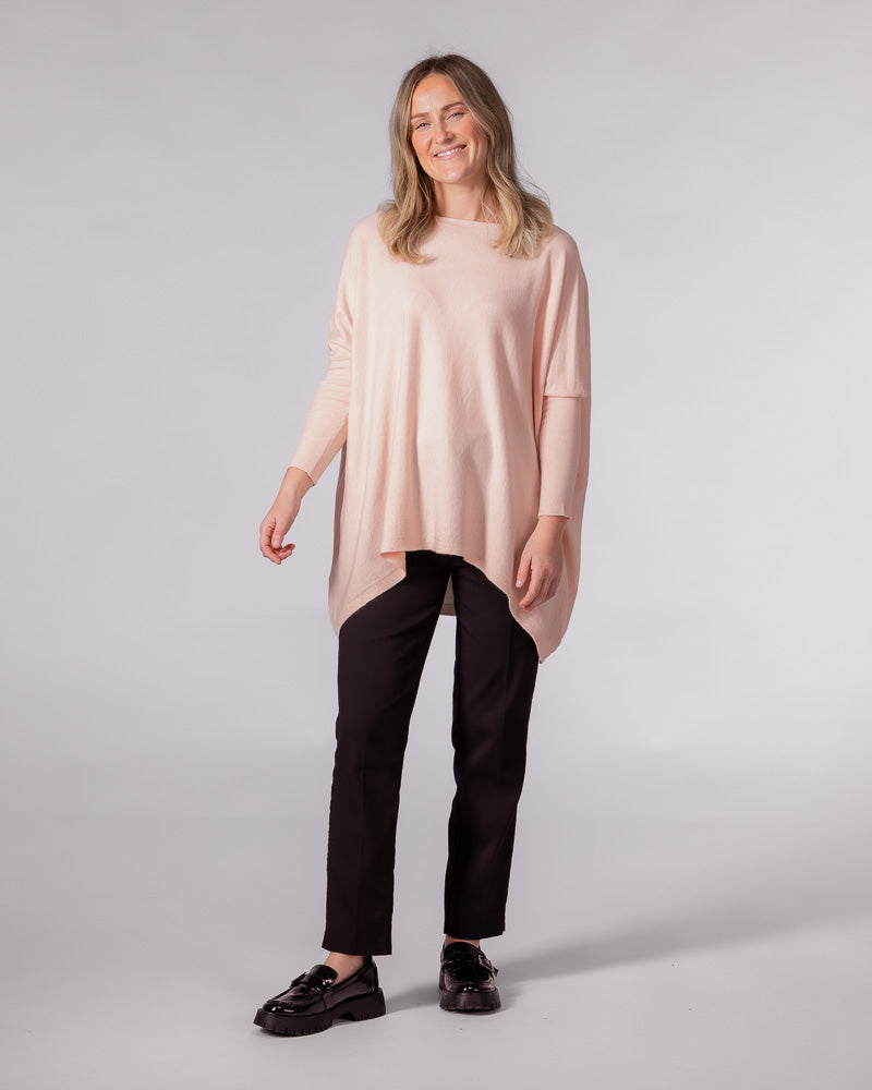Soft pink oversized cotton jumper featuring a wide boat neckline, drop shoulders, fitted sleeves, and a hi-low hem.