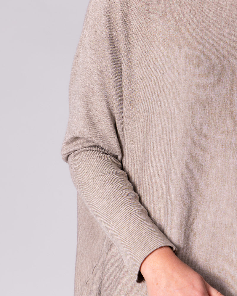 Close-up of the taupe knit top, displaying the contrast between the long fitted ribbed sleeves and loose body.
