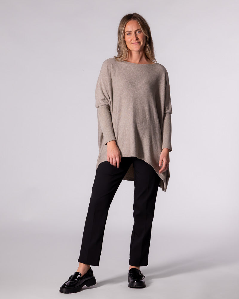 Full-length styling of the oversized taupe knitwear paired with tailored black pants and chunky black loafers.