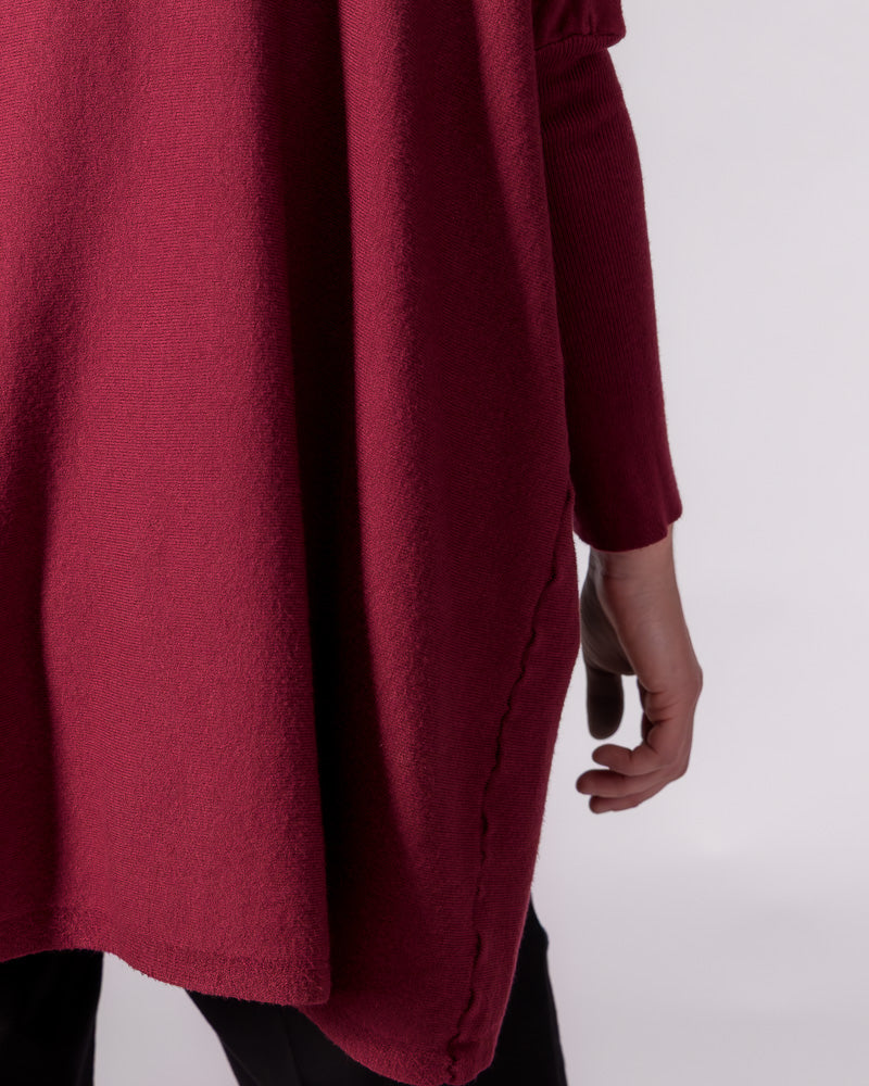 Draped oversized silhouette of the wine red cotton knit jumper, featuring a visible side seam and long fitted sleeve.