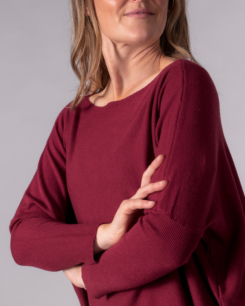 Wine red cotton knit jumper featuring a wide boat neckline, drop shoulders, and fitted ribbed lower sleeves.