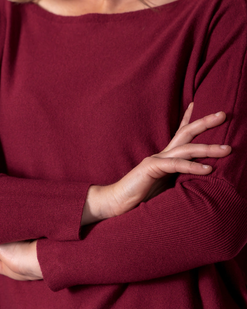 Wine red fine cotton knit jumper showcasing a wide boat neckline, drop shoulder seams, and fitted ribbed sleeves.