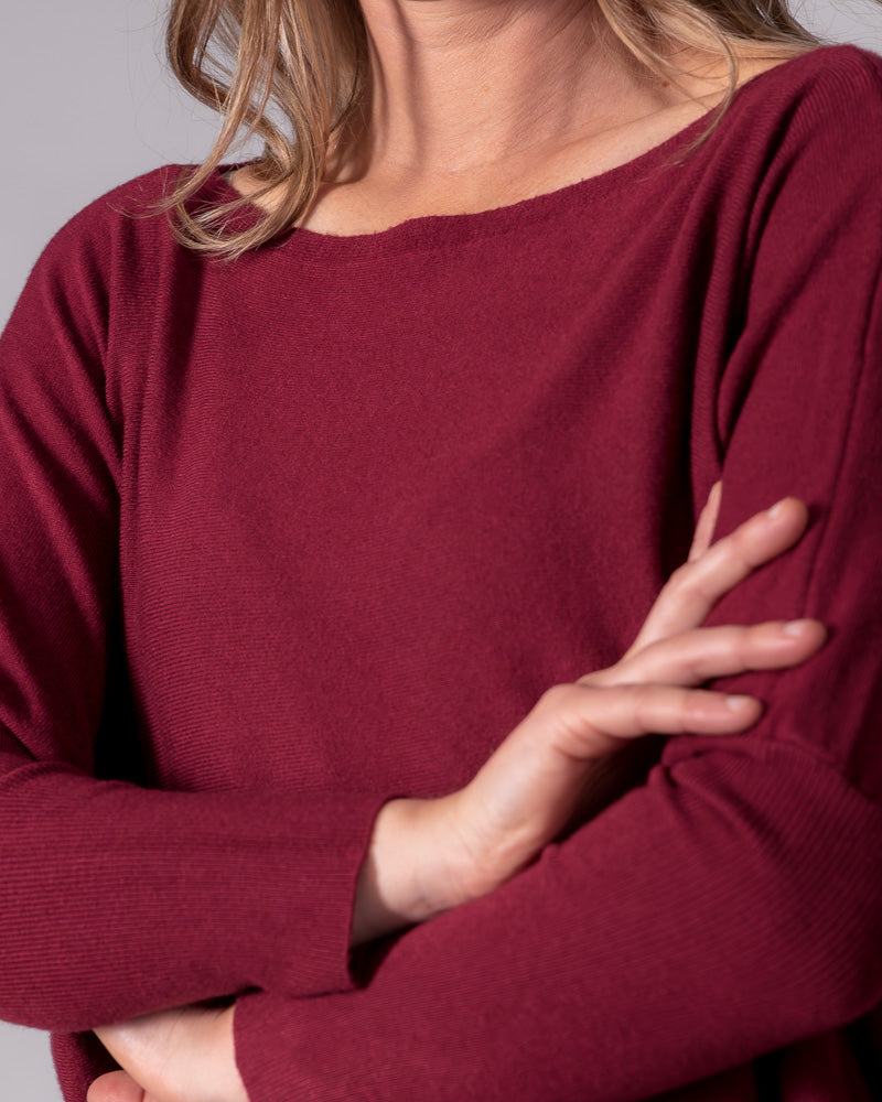 Wine red fine cotton knit jumper highlighting a wide boat neckline, drop shoulder seams, and fitted ribbed sleeves.