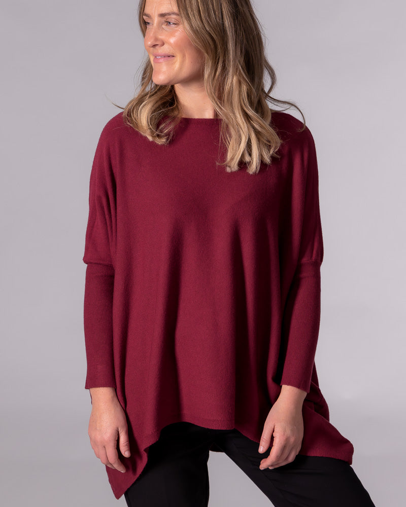 Oversized wine red cotton knit jumper with a wide boat neck, drop shoulders, fitted ribbed sleeves and a hi-low hem.