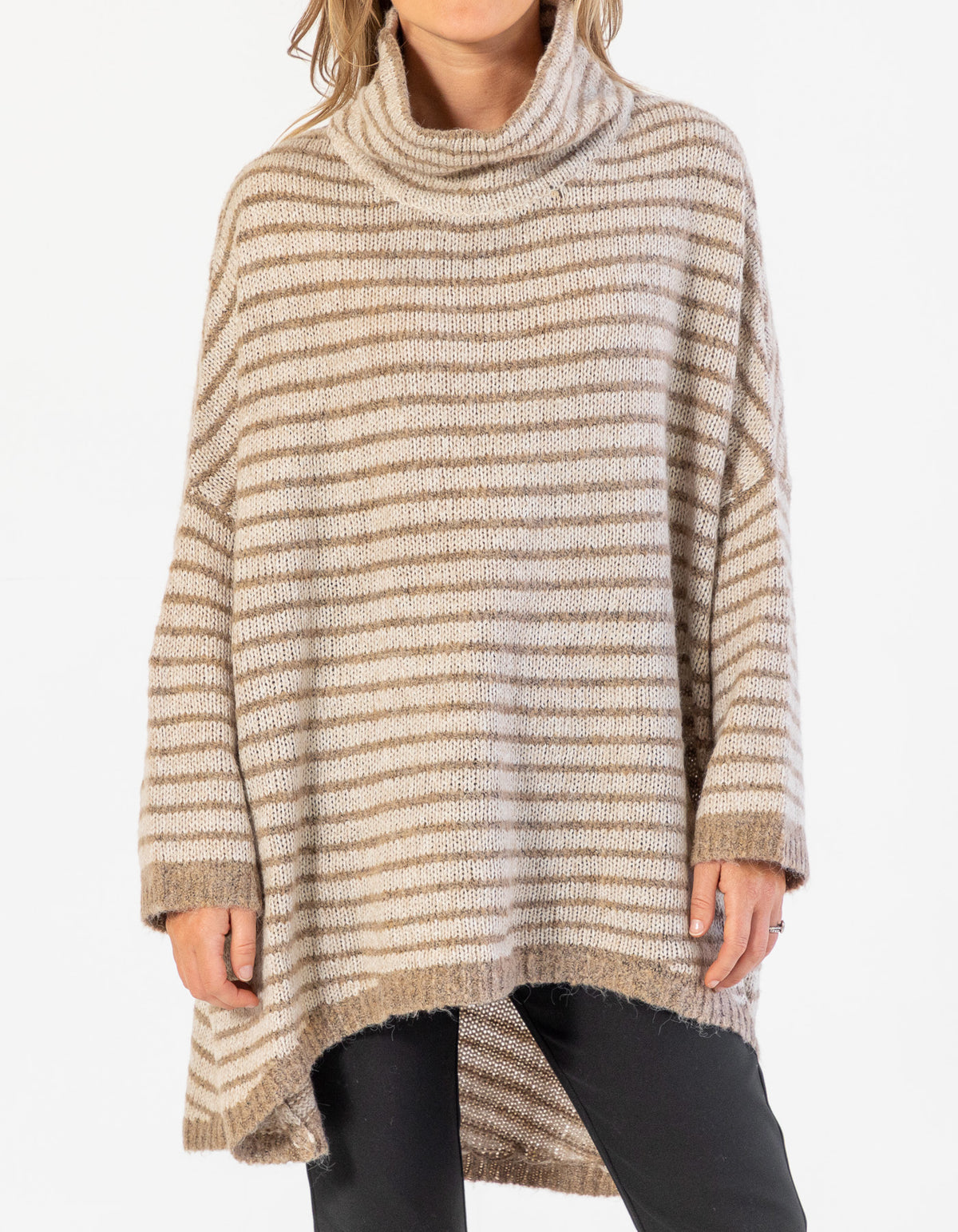 Front half-body shot of the beige and mocha stripe jumper highlighting the scooped hem and black pants.