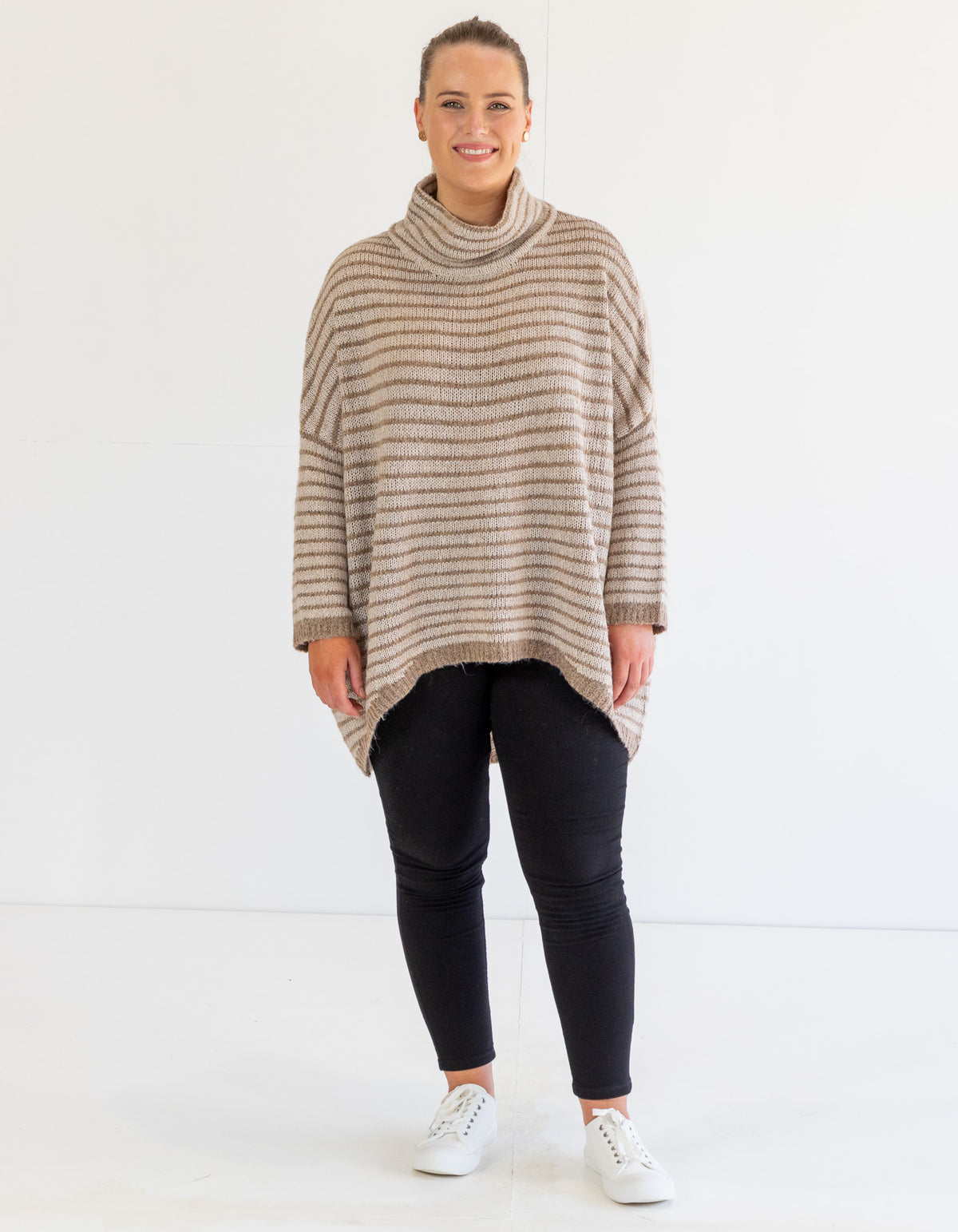 Full-length view of the beige and mocha stripe jumper highlighting the oversized fit and white sneakers.