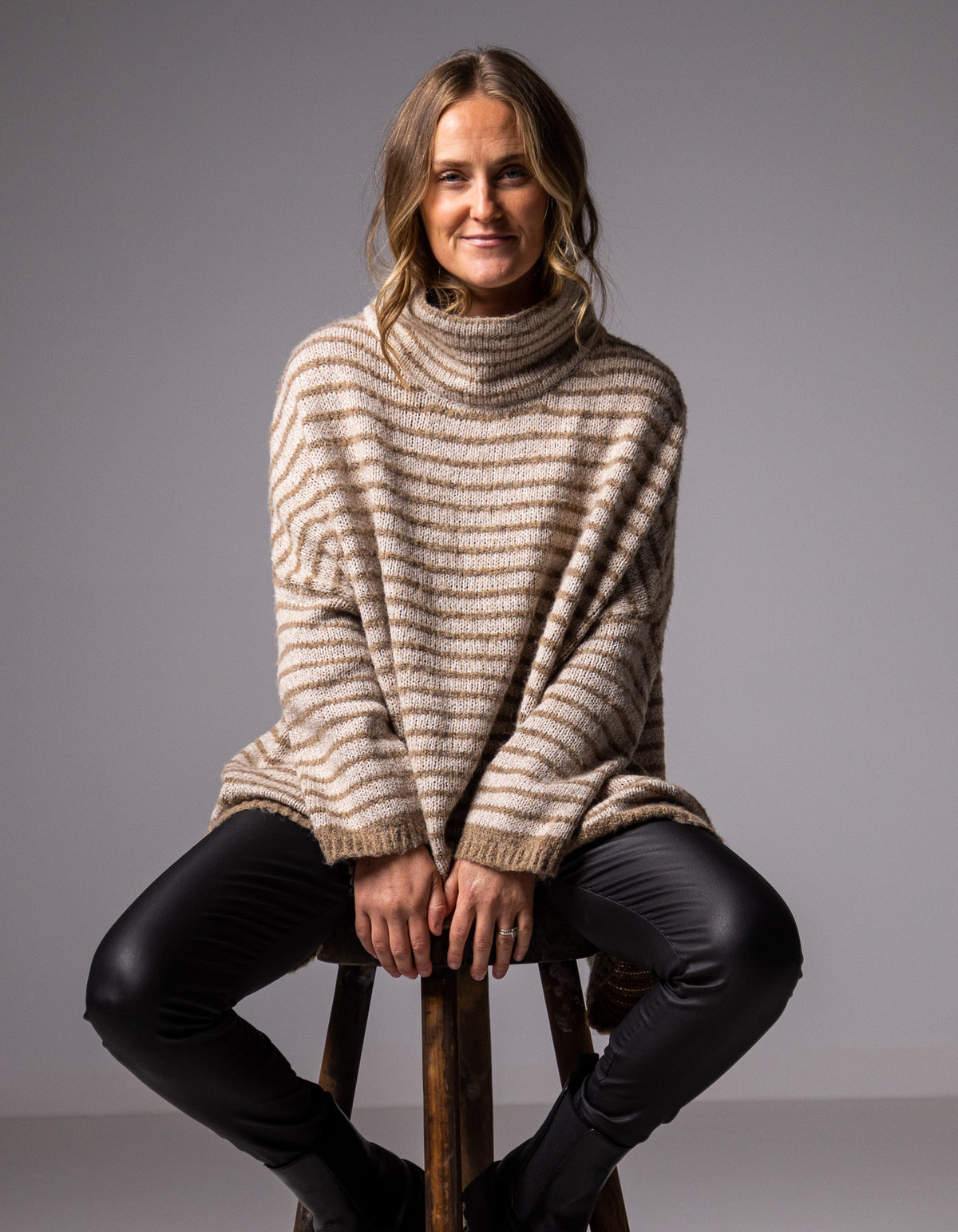 Full-body shot of the beige and mocha stripe jumper styled with black pants and loafers.